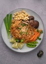 Vertical shot of servings of delicious noodles with salad, lime, greens, carrot, and crumbs