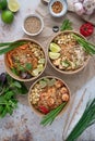 Vertical shot of servings of delicious noodles with salads, lime, greens, seafood, and crumbs