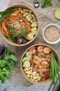 Vertical shot of servings of delicious noodles with salads, lime, greens, seafood, and crumbs