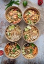 Vertical shot of servings of delicious noodles with salads, lime, greens, seafood, and crumbs