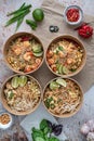 Vertical shot of servings of delicious noodles with salads, lime, greens, seafood, and crumbs