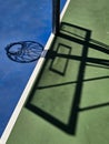 Vertical shot of the shadow of a basketball hoop on a sunny court