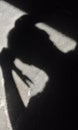 Vertical shot of a shadow of a person holding scissors on the concrete surface