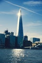 Vertical shot of the Shard skyscraper from the water under a blue sky in London, UK.