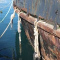 Vertical shot of a ship standing at the harbor tied with white knots