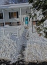 Vertical shot of a shoveled walkway to a turquoise door in front of a house after a big snowstorm Royalty Free Stock Photo