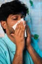 Vertical shot of sick man with sneezed using napkin during cold fever at home - concept of influenza, health care and