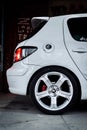 Vertical shot of a side view of a white car with a wheel parked outdoors