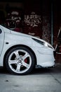 Vertical shot of a side view of a white car with a wheel parked outdoors