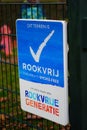 Vertical shot of sign in Dutch language saying that the area is smoking-free by a playground