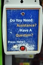 Vertical shot of a sign encouraging to apply for assistance by pressing a red pushbutton