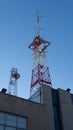 Vertical shot of a signal tower on top of the building on a cloudless day