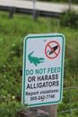 Vertical shot of a signboard with inscriptions on it: Do not feed or harass alligators