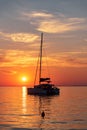 Vertical shot of a silhouette of a boat sailing in the ocean in a vibrant sunset sky background Royalty Free Stock Photo