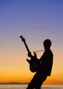 Vertical shot of a silhouette of a cool guitar player on a sunset background