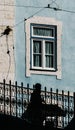 Vertical shot of the silhouette of a person passing blue wall with window