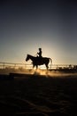 Vertical shot of silhouettes of a rider training on her horse at sunset on a ranch in California Royalty Free Stock Photo