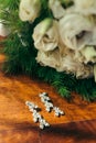 The vertical shot of the silver earrings with diamonds near the beautiful wedding bouquet of white roses on the table Royalty Free Stock Photo