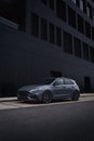 Vertical shot of a sleek gray sports car parked near a black building