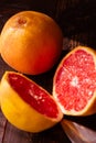 Vertical shot of sliced and whole fresh, juicy seasonal grapefruits and a knife on a wooden table