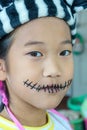 Vertical shot of a small Asian girl with black skull makeup for Halloween