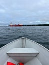 Vertical shot from a small boat, of a big ship sailing at Lawrence River under cloudy sky Royalty Free Stock Photo