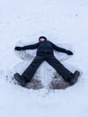 Vertical shot of a small child doing snow angles on a field