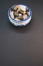 Vertical shot of small colorful rocks in a china bowl on a black surface Royalty Free Stock Photo