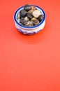 Vertical shot of small colorful rocks in a china bowl on a peach-colored surface Royalty Free Stock Photo