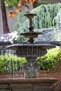 Vertical shot of the small fountain filled with water in the garden filled with various colors. Royalty Free Stock Photo