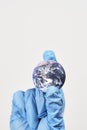 Vertical shot of a small globe in the hand of a person in a blue plastic glove