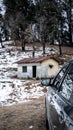 Vertical shot of a small house in the forest and a car parked near it Royalty Free Stock Photo