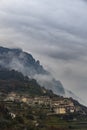 Vertical shot of a small Italian village on a mountain surrounded by fog Royalty Free Stock Photo