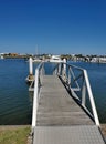 Vertical shot of a small pier in the marina, docked boats in the background