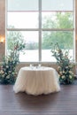 Vertical shot of a small table with tulle and two floral compositions in the wedding hall