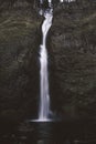 Vertical shot of a small waterfall in the center of the mossy rocks Royalty Free Stock Photo