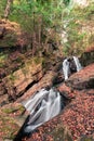 Vertical shot of a small waterfall flowing over rocks in a forest Royalty Free Stock Photo