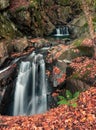 Vertical shot of a small waterfall flowing over rocks in a forest Royalty Free Stock Photo