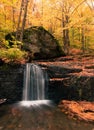 Vertical shot of a small waterfall flowing over rocks in a forest Royalty Free Stock Photo