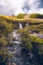 Vertical shot of a small waterfall in the green woods of Ilse of Skye, Scotland under a cloudy sky Royalty Free Stock Photo