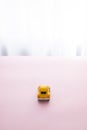 Vertical shot of small yellow toy car on a beautiful surface, rear view Royalty Free Stock Photo