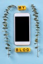 Vertical shot of smartphone with cube letters and branches.