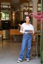Vertical shot of smiling asian businesswoman, waitress standing in front of cafe entrance, inviting guests in restaurant Royalty Free Stock Photo