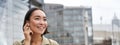 Vertical shot of smiling asian woman in wireless headphones, enjoys listening to music in earphones, holds mobile phone Royalty Free Stock Photo