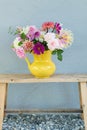 Vertical shot of a soft floral bouquet in a yellow vase on a wooden console table Royalty Free Stock Photo