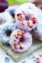 Vertical shot of some purple and blue vegan donuts covered with edible rose flowers Royalty Free Stock Photo