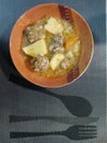 Vertical shot of soup of meatballs with potato and squash in a bowl on a placemat