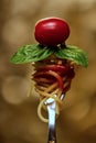 Vertical shot of spaghetti on a fork with basil, tomato, and sauce on a blurred background Royalty Free Stock Photo