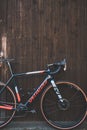 Vertical shot of a specialized Crux bicycle leaning on a wooden wall