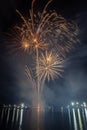 Vertical shot of a Spectacular night sky with an array of fireworks exploding over a body of water Royalty Free Stock Photo